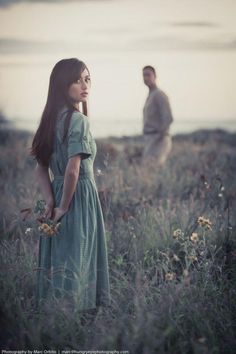 a woman standing in a field next to a man