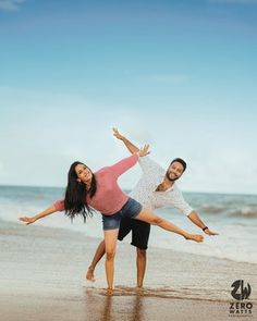 a man and woman are dancing on the beach with their arms in the air while holding each other's leg