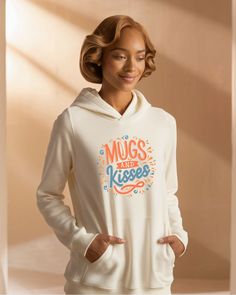 a woman wearing a white hoodie with the words mugs and kisses on it