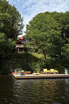 a house boat floating on top of a lake next to a lush green tree covered hillside