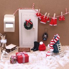 a christmas scene with stockings and presents on the ground next to a mailbox, snowman's hat, ladder, santa clauss