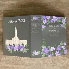 the book of mormon with purple flowers on it and an image of a church in the background