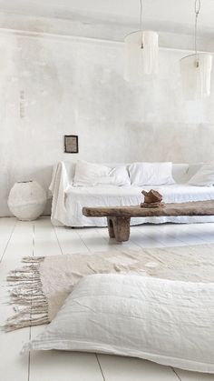 a white room with a bed, table and rugs