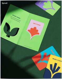 four different colored cards sitting next to each other on a green surface with shadows coming from them