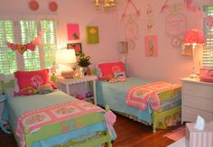 two twin beds in a girls bedroom with pink and green decorations on the wall above them