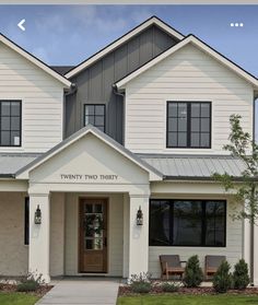 a white two story house with black trim and windows on the front door is shown