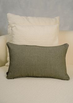 a close up of a pillow on a bed with white sheets and pillows in the background