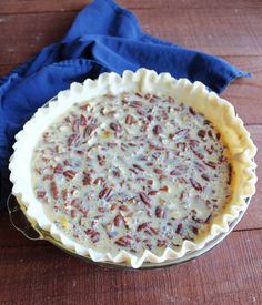 a pie sitting on top of a wooden table next to a blue napkin and fork