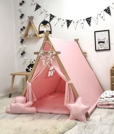 a pink teepee tent sitting on top of a floor next to pillows and blankets