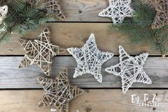 three star shaped ornaments are hanging on a wooden table with pine branches and twine