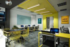 an office with yellow chairs and laptops