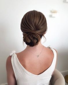 a woman sitting in a chair with her back turned to the camera, wearing a white dress