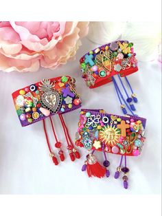 three colorful bracelets sitting on top of a white table next to a pink flower