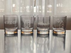 three shot glasses sitting on top of a table next to each other with the word detroit etched in them