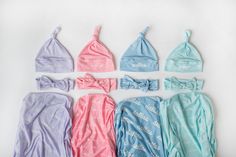 six baby swaddles are laid out on a white surface, including one blue and one pink