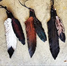 three different colored feathers hanging from a leather cord