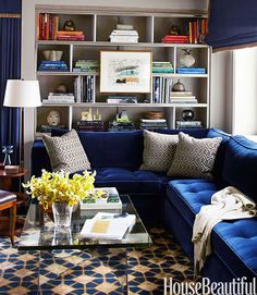 a living room filled with blue couches and a coffee table in front of a window