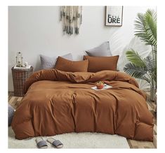 a bed with brown sheets and pillows in a room next to a potted plant