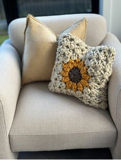 a crocheted sunflower pillow sitting on a chair