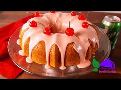 a bundt cake with white icing and cherries on top sitting on a glass plate