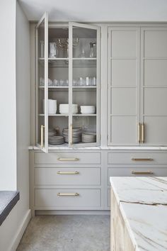 a kitchen with white cabinets and marble counter tops, gold pulls on the doors, and brass handles