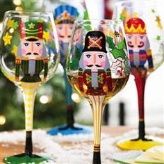 three wine glasses with nutcrackers painted on them sitting in front of a christmas tree