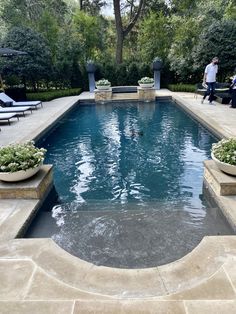 an outdoor swimming pool surrounded by stone steps and planters with water running through it