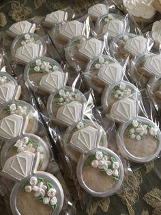 many decorated cookies in plastic wrappers on a table with flowers and leaves around them