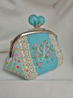 a blue purse with lace and flowers on it sitting on a white cloth covered surface