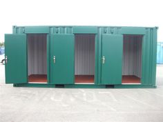 three green storage containers sitting in the middle of a parking lot