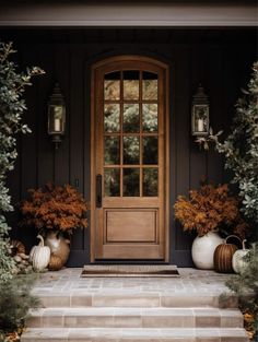 a front door with two large vases on the steps