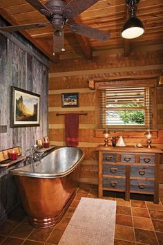 a bathroom with a copper bathtub and ceiling fan