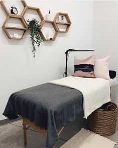 a bed with a blanket on top of it next to a basket and wall hangings