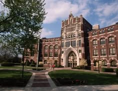 a large brick building with many windows on it's sides and trees in the foreground