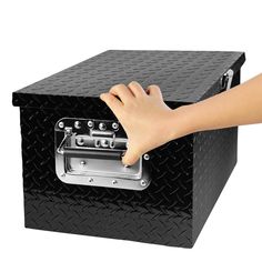 a person's hand reaching into a black toolbox with diamond patterning on it