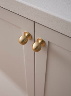 two gold knobs on the front of a white cabinet