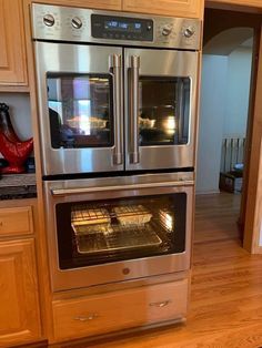 an oven built into the wall in a kitchen with wooden cabinets and hardwood flooring