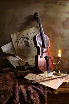 a violin, candle and music sheets on a table