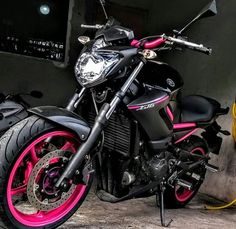 a black and pink motorcycle parked next to a yellow fire hydrant