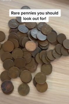 a pile of coins sitting on top of a wooden table next to a sign that says rare pennies you should look out for