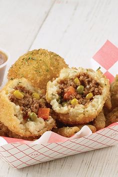 a basket filled with fried food next to a cup of coffee