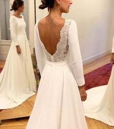 the back of a woman's wedding dress in front of a mirror