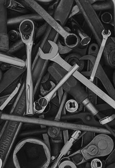 black and white photograph of various wrenches and spanner's tools in a pile