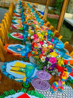 a long table is decorated with brightly colored paper flowers and napkins for an outdoor party