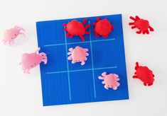 red and pink plastic sea animals sitting on top of a blue board with squares in the middle