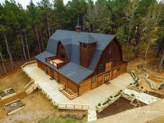 an aerial view of a large wooden house in the middle of a forest with lots of trees