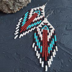 a pair of beaded earrings sitting on top of a rock