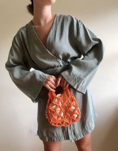 a woman in grey dress holding an orange purse