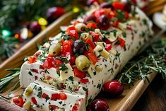 an appetizer with olives, tomatoes and cheese on a wooden platter