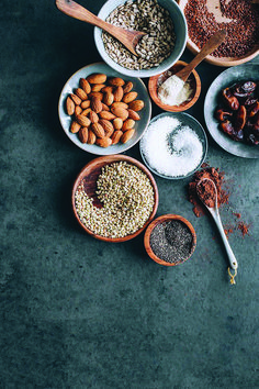 nuts, seeds and other ingredients are arranged in bowls on a gray surface with spoons